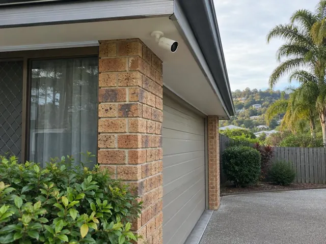 Exterior CCTV camera mounted under the eave above a brick garage wall in Elanora
