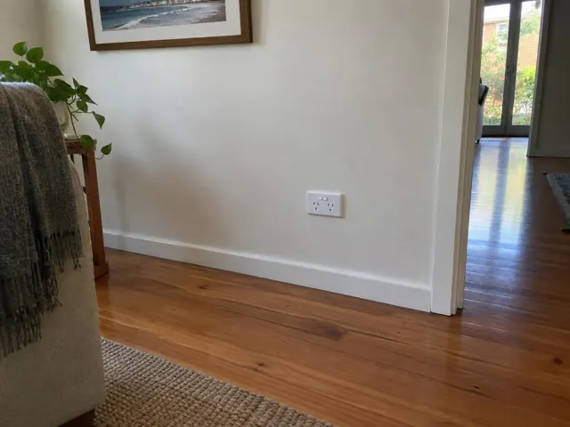 New white double power point on a painted wall beside timber flooring in a home interior in Burleigh Heads